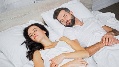 Sakallı adam ve esmer kadın evde birlikte uyuyorlar.