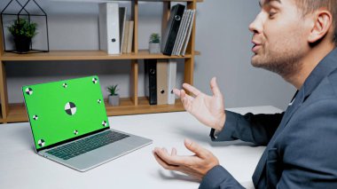 Bulanık arkaplanda video görüşmesi sırasında iş adamının yanında konuşan krom anahtarlı dizüstü bilgisayar 