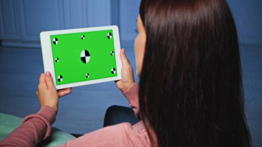 Bulanık ön plandaki kadının ellerinde kroma anahtarı olan dijital tablet 