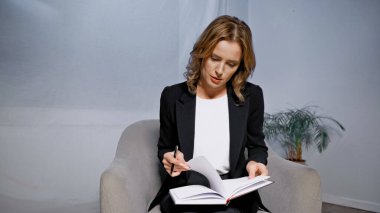 Ofisteki koltukta oturan kalem ve defter yöneticisi 