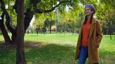 Şık bir sonbahar elbisesi içinde mutlu bir kadın. Parkta el ele dolaşıyor.