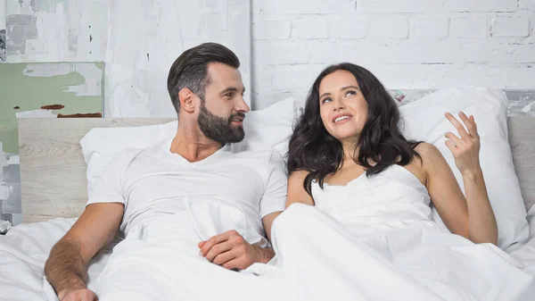 Smiling Brunette Woman Gesturing While Talking Bearded Boyfriend Bed — Stock Photo, Image