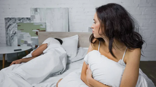 伤心的年轻女人看着男朋友睡在床上 — 图库照片