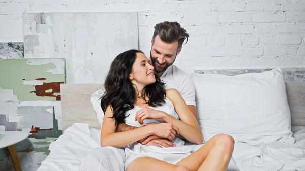 Bearded Man Embracing Happy Brunette Girlfriend Bedroom — Stock Photo, Image