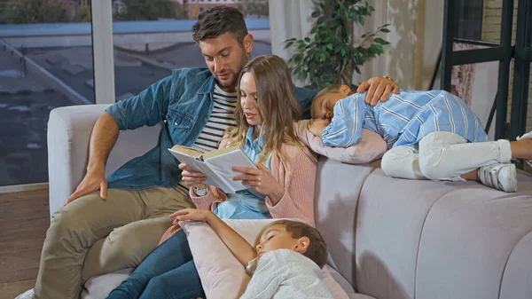 Mujer Leyendo Libro Cerca Marido Hijos Durmiendo Sala Estar —  Fotos de Stock