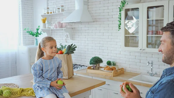 Girl Holding Apple Father Blurred Foreground Kitchen — Stock Photo, Image
