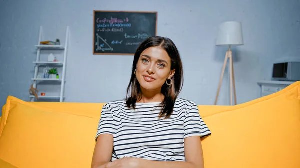 Brunette Woman Smiling Camera Bright Yellow Couch — Stock Photo, Image