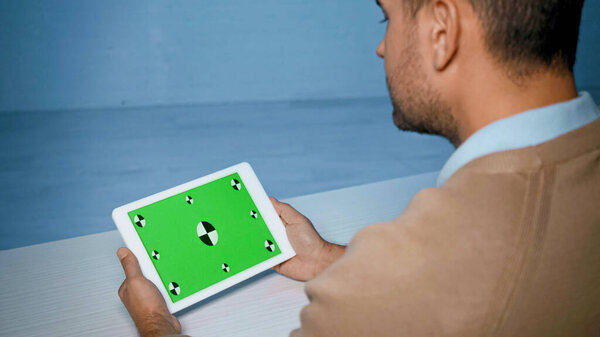Digital tablet with green screen in hands of man on blurred foreground 