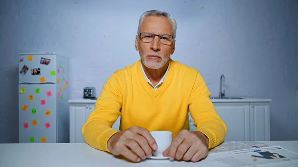 Älterer Mann Mit Brille Hält Kaffeetasse Neben Zeitung Auf Verschwommenem — Stockfoto