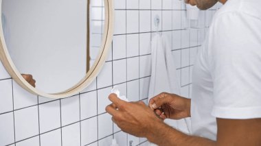 Banyoda aynanın yanında diş ipi tutan bir adam vardı.