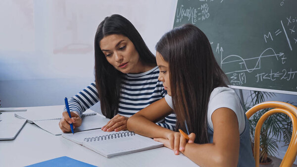 mother and daughter looking at notebook while doing homework at home