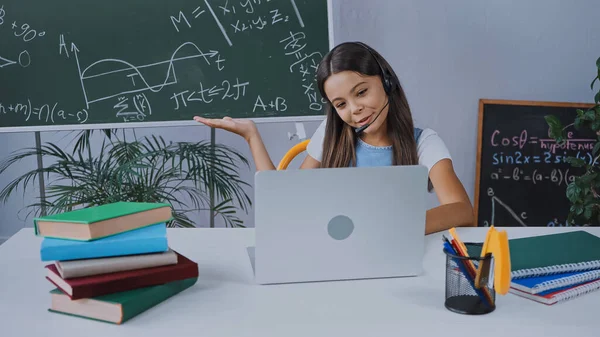 Щасливий Школяр Гарнітурі Дивлячись Ноутбук Вказуючи Рукою Дошці — стокове фото