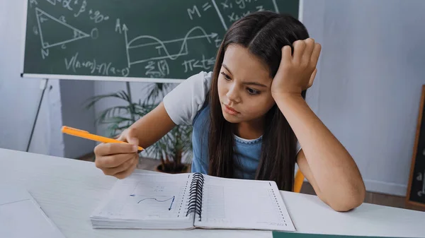 Displeased Kid Holding Pen Looking Notebook Graph — Stock Photo, Image