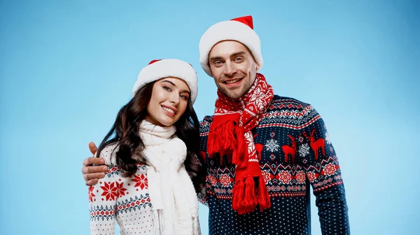 Glimlachend Paar Truien Santa Hoeden Knuffelen Blauwe Achtergrond — Stockfoto