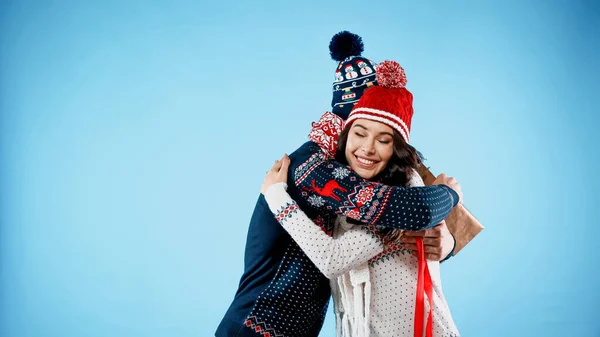 Smiling Woman Hat Sweater Hugging Boyfriend Gift Box Blue Background — Stock Photo, Image