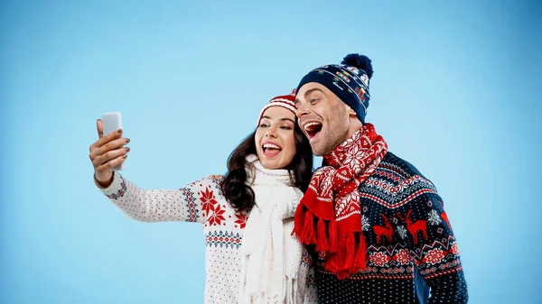 Młoda Para Ciepłych Ubraniach Robi Selfie Smartfonie Niebieskim Tle — Zdjęcie stockowe