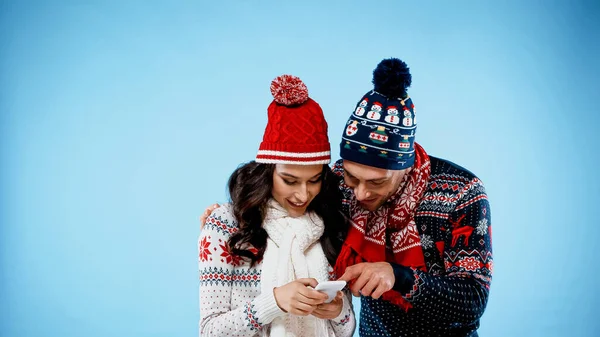 Lächelndes Paar Warmer Kleidung Mit Smartphone Auf Blauem Hintergrund — Stockfoto