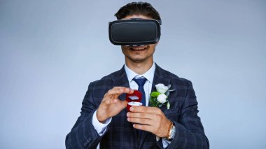 smiling groom in vr headset opening jewelry box with wedding ring isolated on blue clipart