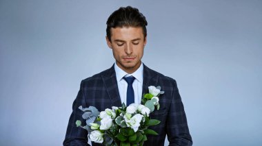 üzgün damat mavi üzerine izole düğün buketi tutuyor