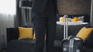 cropped view of businesswoman standing near suitcase clipart