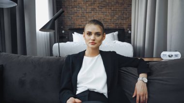 businesswoman in formal wear sitting on sofa in hotel clipart