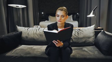 businesswoman in formal wear looking at notebook in hotel room clipart