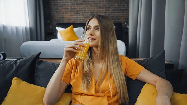 ホテルの部屋でオレンジジュースを飲む若い女性 — ストック写真