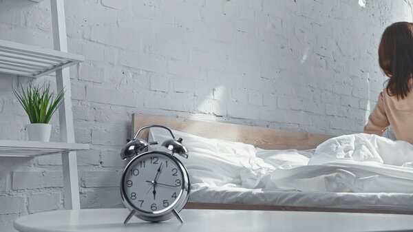 retro alarm clock near woman getting up from bed in morning 