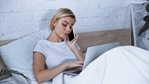 Genç Serbest Çalışan Dizüstü Bilgisayar Kullanıyor Yatak Odasında Cep Telefonuyla — Stok fotoğraf