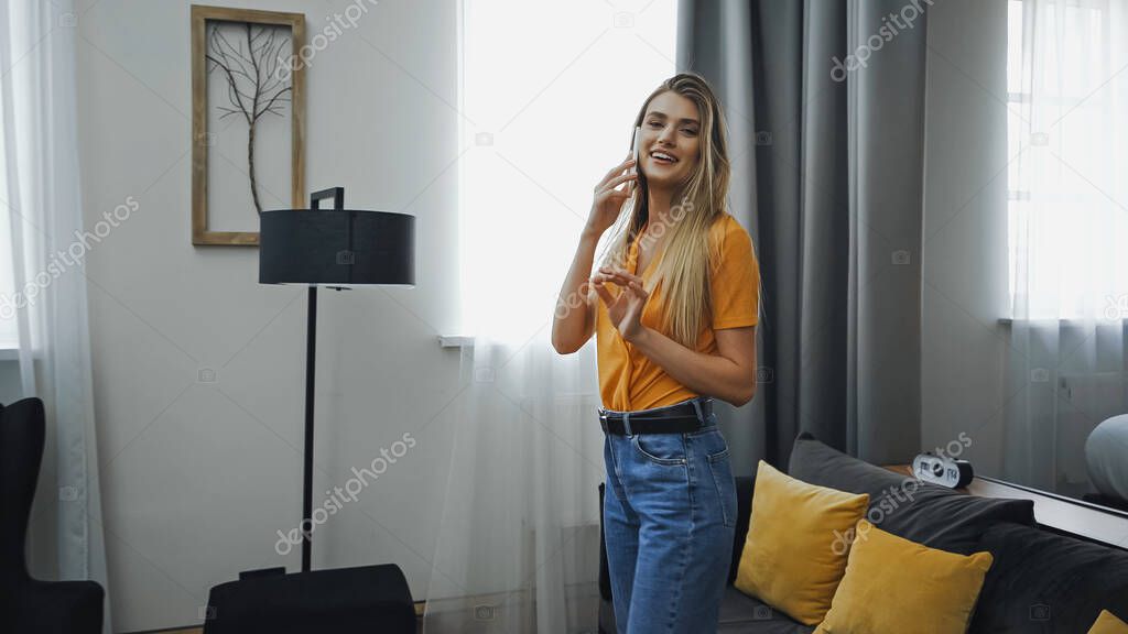 cheerful woman talking on smartphone in hotel room 