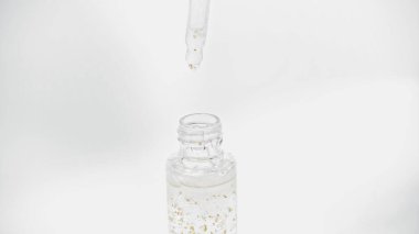 close up of pipette above glass bottle with essential oil on white clipart