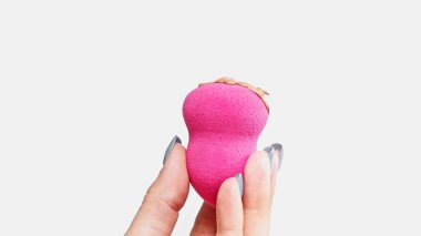 cropped view of woman holding beauty blender sponge with makeup foundation isolated on white clipart