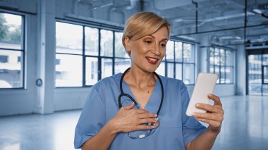 Klinikte akıllı telefondan video görüşmesi yapan olgun bir doktor. 