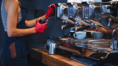 cropped view of barista in latex gloves holding pitcher near steam wand clipart