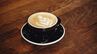 Bir fincan lezzetli kapuçino ve masada latte sanatı.