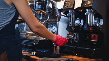 cropped view of barista holding portafilter with ground coffee clipart