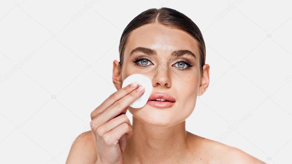 Young woman removing makeup with soft cotton pad isolated on white