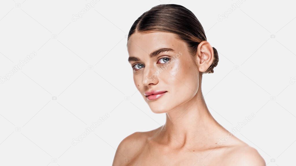 brunette young woman with clean face and glowing cheek looking at camera isolated on white