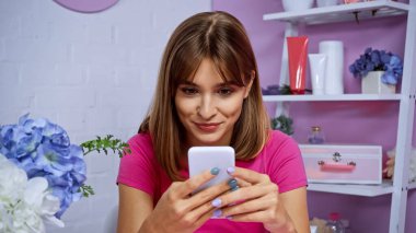 cheerful young woman with piercing texting on smartphone  clipart