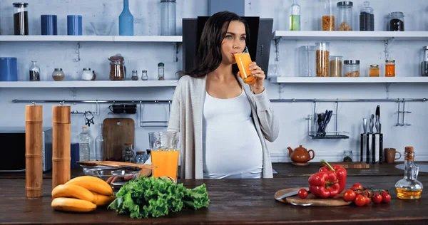 Mulher Grávida Bebendo Suco Laranja Perto Alimentos Orgânicos Cozinha — Fotografia de Stock