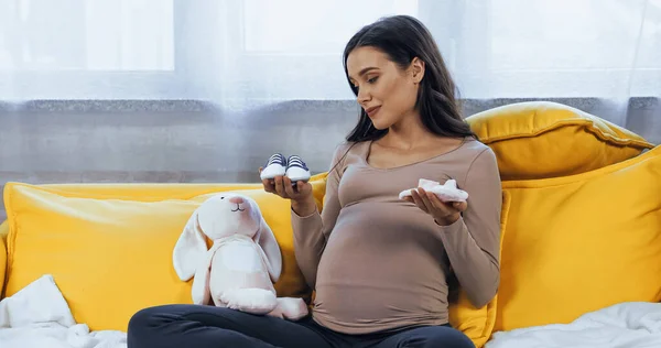 Gravid Kvinne Med Babystøvler Nærheten Mykt Leketøy Hjemme – stockfoto