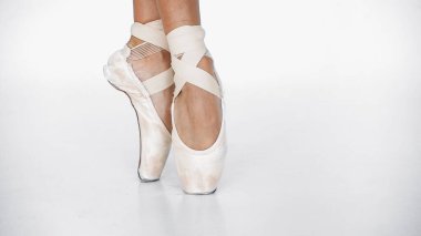 partial view of ballerina in pointe shoes dancing on white clipart