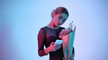 Çiçek tutan balerin mavi üzerine akıllı telefon kullanıyor. 