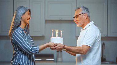 Mutlu Asyalı karısından doğum günü pastası alan mutlu kıdemli adamın yan görüntüsü