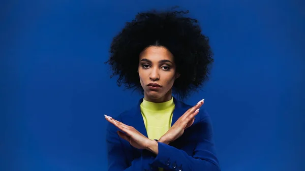 African american woman showing stop gesture isolated on blue