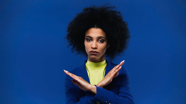 African american woman showing stop gesture isolated on blue