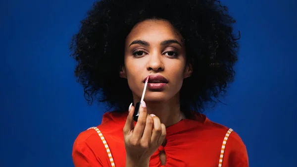 Mujer Afroamericana Joven Aplicando Brillo Labial Aislado Azul — Foto de Stock