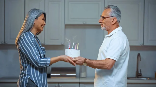 Боковой Вид Счастливой Пожилой Женщины Принимающей Именинный Торт Улыбающегося Мужа — стоковое фото