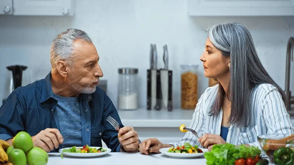 Senior Interracial Couple Talking While Eating Fresh Salad Kitchen — Stock Photo, Image