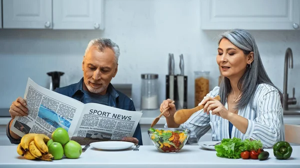 Oudere Aziatische Vrouw Mengen Salade Buurt Van Man Lezen Sport — Stockfoto